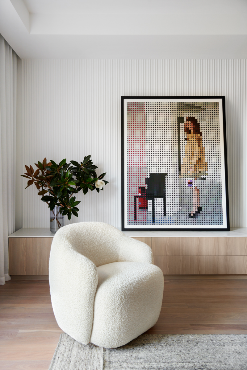 Scandinavian living corner with bouclé armchair, ribbed wall panelling, framed art and soft neutral tones.