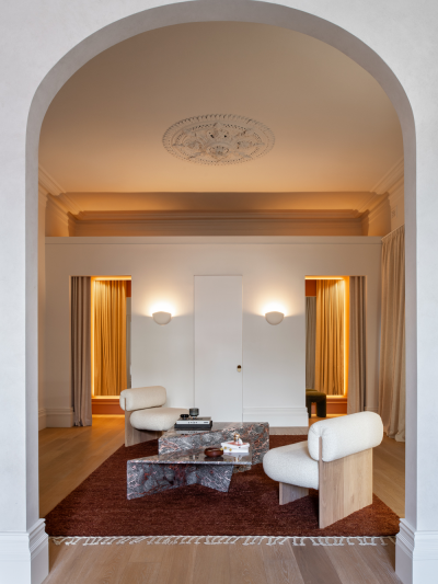 Scandinavian retail interior with arched doorway, warm ambient lighting, sculptural lounge chairs and a calm neutral palette.