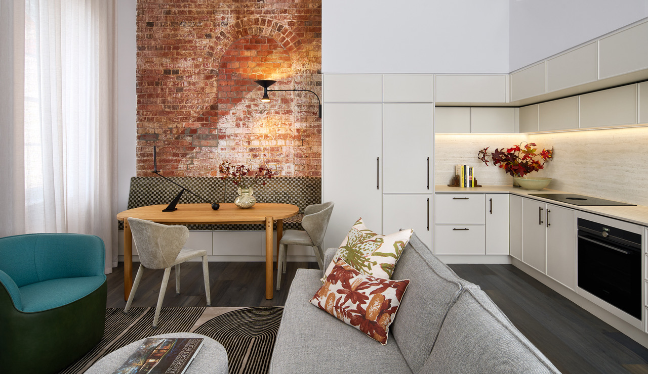 Industrial heritage kitchen with exposed brick arch and modern cabinetry designed for listed building consent in London.